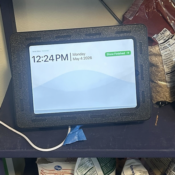 Our device in a plastic pantry shelf. In the middle is our device - a screen in a 3D printed case.